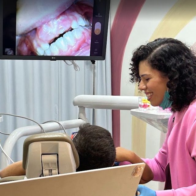 Dentista sorrindo enquanto olha a tela com a criança