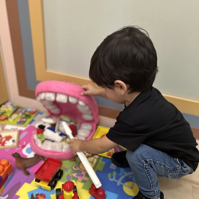 Menino brincando no chão com o boneco de dentes