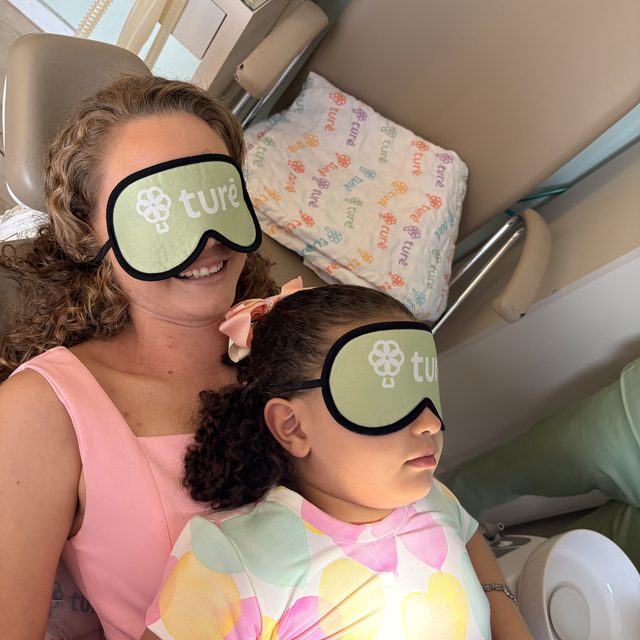 Mãe e filha deitadas na cadeira, as duas com a máscara da Clínica Turê